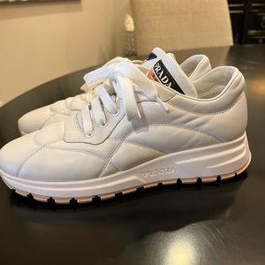 Prada Womens white quilted leather sneaker with light pink sole and trim.